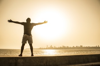 Man Standing on Ledge While Spreading Arms