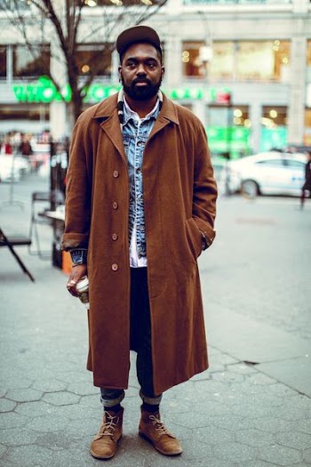 man standing on road near bare tree