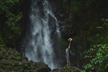 Man Standing On Rock Facing Waterfalls