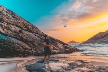 Man Standing on Rock Flying a Drone