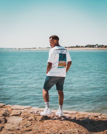 man standing on rock formation beside body of water