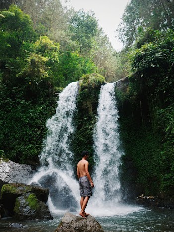 Man Standing on Rock in Front of Waterfalls