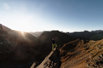 Man Standing on Rock on Top of Mountain Facing Sun
