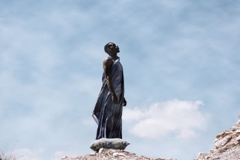 Man Standing on Rocky Ground Looking Up