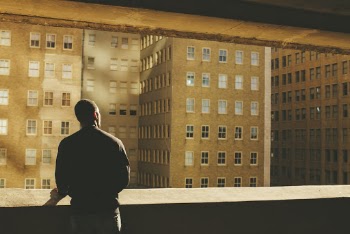 Man Standing on Rooftop Facing Brown Highrise Building
