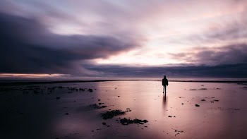man standing on sand under dark sky