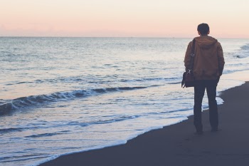 Man Standing on Seashore While Carrying Bag