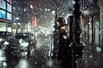 man standing on sidewalk during snowfall