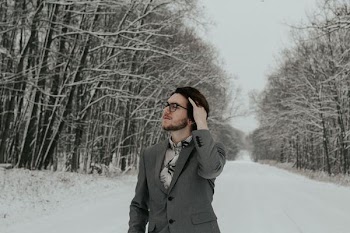 man standing on snow field while touching hair