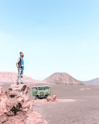 Man Standing on Top of Rock Near Parked Green Toyota Land Cruiser Fj40