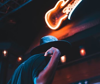 man standing under Budweiser signage at nighttime