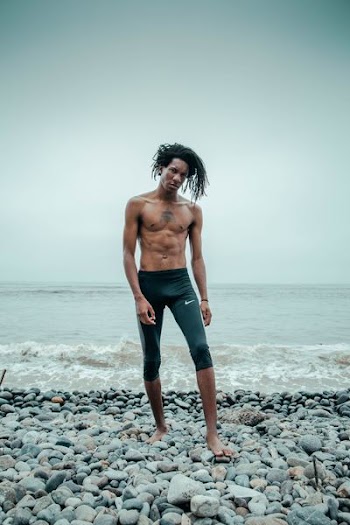 man standing wearing black Nike shorts near the beach