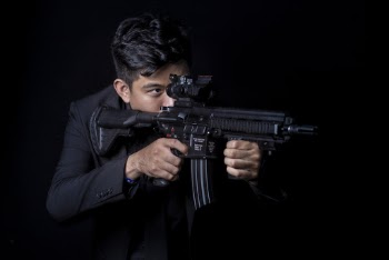 Man Standing While Aiming Rifle