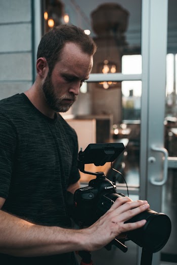 Man Standing While Holding Black Dslr Camera