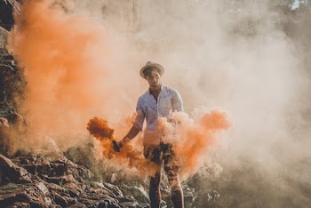 Man Standing While Holding Smoke Grenades 