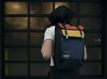 Man Standing While Wearing Black, Red, and Yellow Backpack