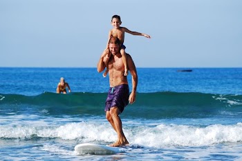 man surfboarding while lifting child