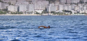 Man Swimming in a Body of Water White Concrete High Rise Building in Background