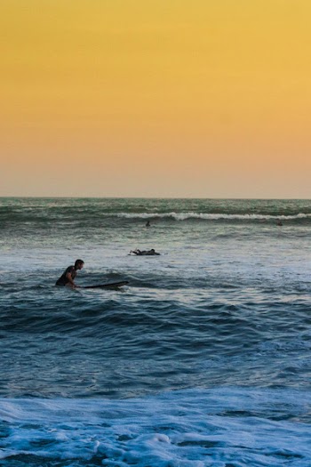 Man Swimming on Sea Under Yellow Sky