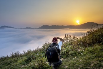 Man Taking Photo of Goldenhour While Kneeling