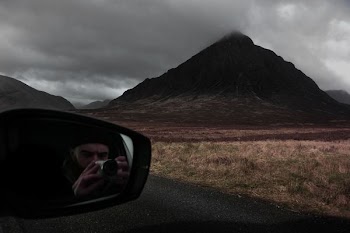 man taking photo of mountain while in car