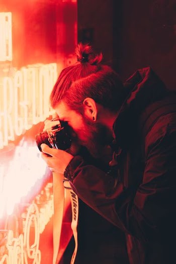 man taking photo of red LED neon signage