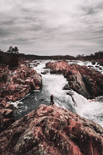 man taking photo of water falls