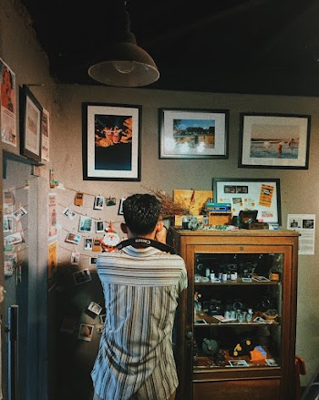 Man Taking Photos of a Wall full of photographs