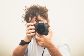man taking pictures using Canon