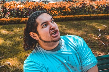 Man Taking Selfie Seating on Green Bench Outdoors