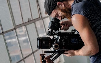 man taking video in front of glass window