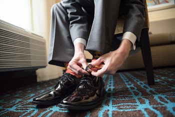Man Tying Shoelace Near White Radiator Panel