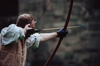 man using brown bow with arrow