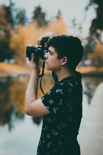 Man Using Camera Near Body of Water