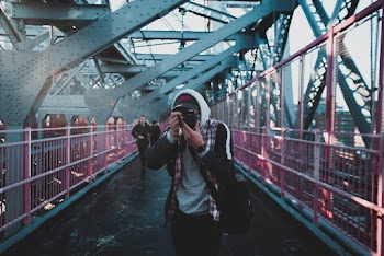 Man Using Camera on Bridge