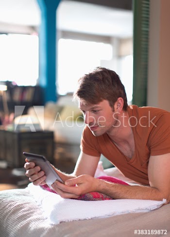 Man using digital tablet on bed