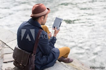 Man using digital tablet on ledge above river