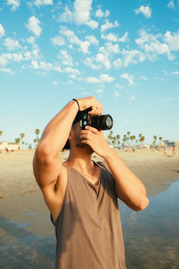 Man Using Dslr Camera While Standing on Seashore