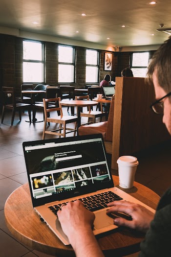 Man Using Macbook on Wooden Table