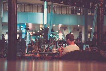 man using phone sitting on chair in front of white mug