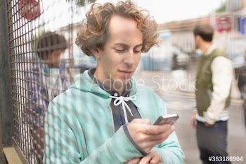 Man using smart phone at fence
