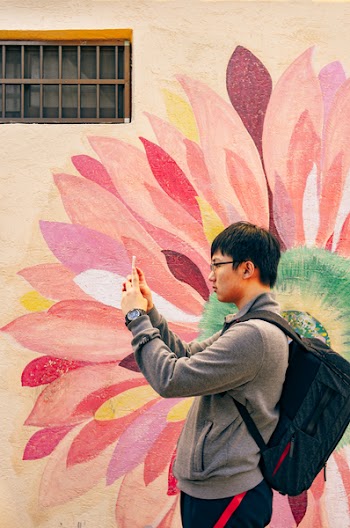 Man Using Smartphone Beside Floral Wall