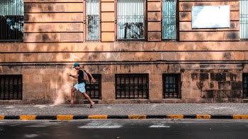 Man Walking at the Walkway Near Curb