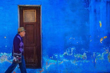man walking beside blue painted building