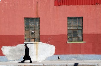 man walking beside red wall