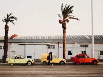 man walking beside three vehicles