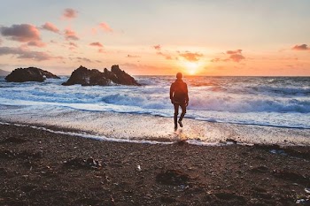 man walking in beach during golden hour