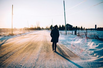 man walking in the middle of the road covered with snow