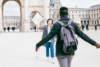 Man Walking Near to Woman Holding Signage