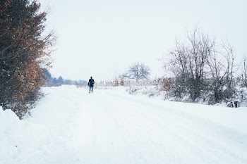 Man Walking on Dirt Road Covered by Snow